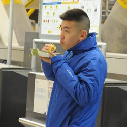 Yong Li ameniza la espera en el aeropuerto comiendo una hamburguesa