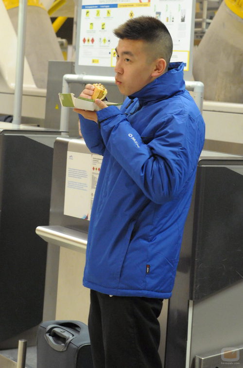 Yong Li ameniza la espera en el aeropuerto comiendo una hamburguesa