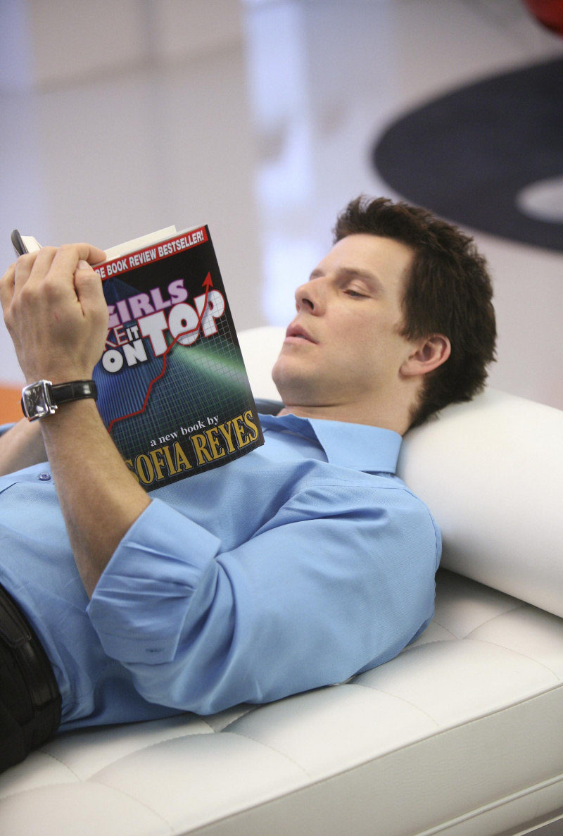 El actor Eric Mabius lee tumbado en 'Ugly Betty'
