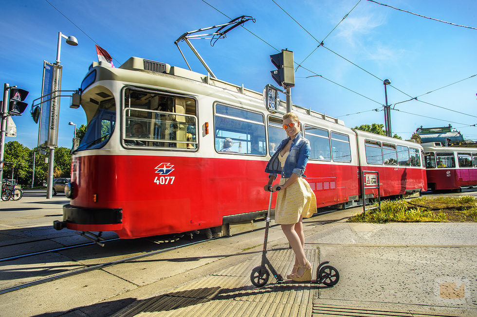 Edurne subida en un patinete, frente a un tranvía, en la ciudad de Viena