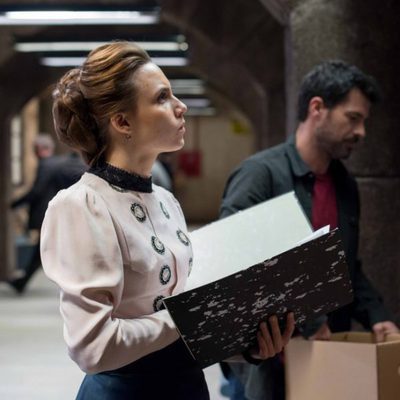 Amelia observa un tablón de anuncios junto a Julián