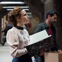 Amelia observa un tablón de anuncios junto a Julián