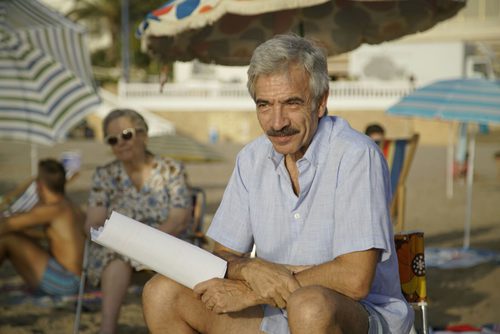 Imanol Arias sujeta un papel mientras se está rodando en la playa 'Cuéntame cómo pasó' en Benidorm