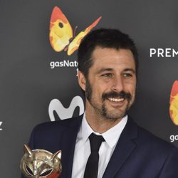 Hugo Silva sonriente con su galardón en la alfombra roja de los Premios Feroz 2017