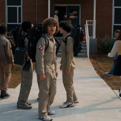 Dustin con los demás chicos, a las puertas del Instituto de Hawkins, vestido como los Cazafantasmas en la segunda temporada de 'Stranger Things'