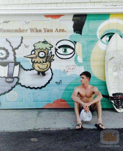 Miguel Bernardeau, sentado junto a su tabla de surf