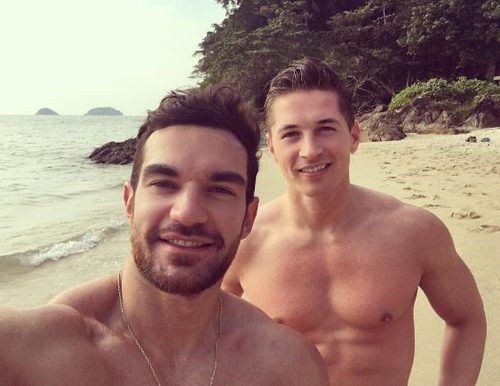 James Longman posa sin camiseta junto a un amigo en la playa