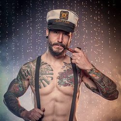 Daniel G. Prim, semidesnudo, con tirantes y una gorra de marinero