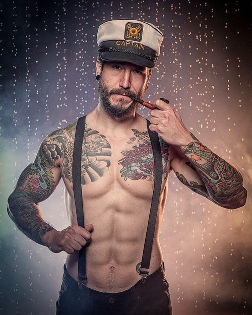 Daniel G. Prim, semidesnudo, con tirantes y una gorra de marinero