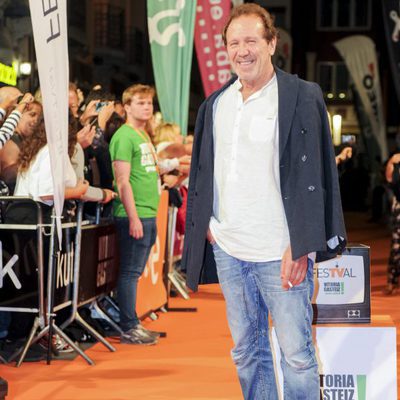 Pose de Juan Gea, actor del 'Ministerio del Tiempo', sonriendo en la alfombra naranja del FesTVal