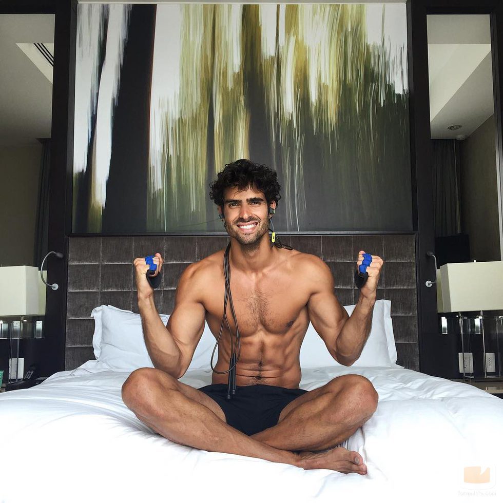 Juan Betancourt sonríe semidesnudo en la cama