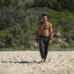 Marco Pigossi como Dylan de 'La tierra de las mareas' pasea por la playa sin camiseta