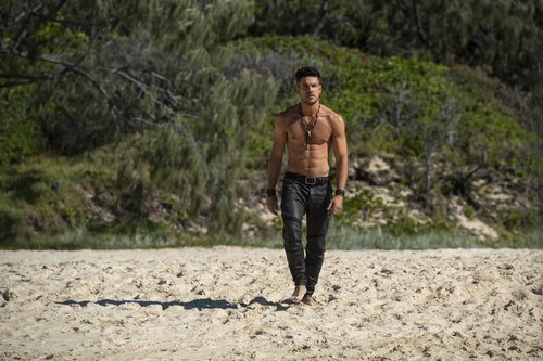 Marco Pigossi como Dylan de 'La tierra de las mareas' pasea por la playa sin camiseta