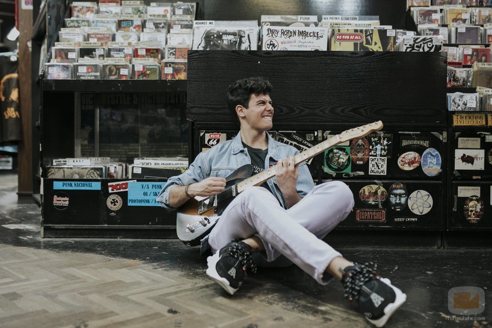 Alfred García posa con su guitarra eléctrica en una tienda de discos