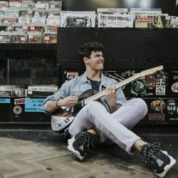 Alfred García posa con su guitarra eléctrica en una tienda de discos