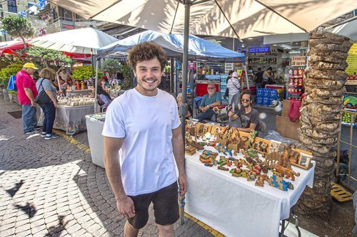 Miki Núñez posando junto a un puesto de artesanía en los mercados de Tel Aviv