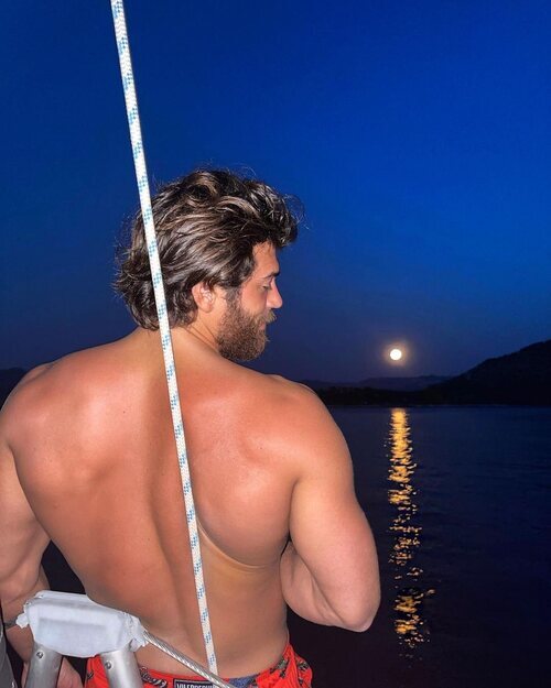 Can Yaman posa de espalda en un barco