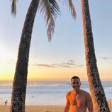 André Lamoglia, sin camiseta, entre dos palmeras