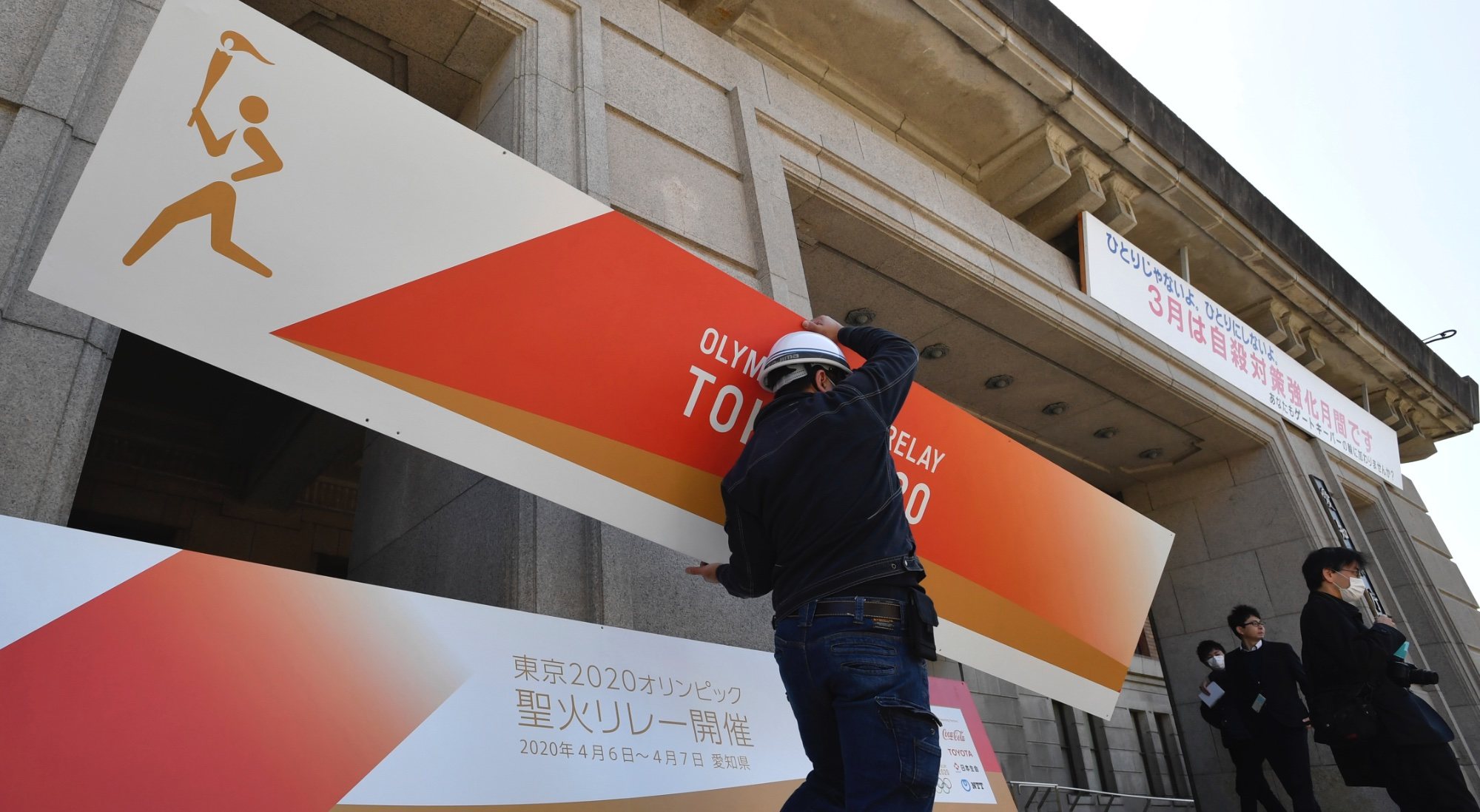 Un operario retirando un cartel de Tokio 2020