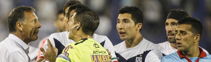 El colegiado siendo asediado por los jugadores de ambas formaciones