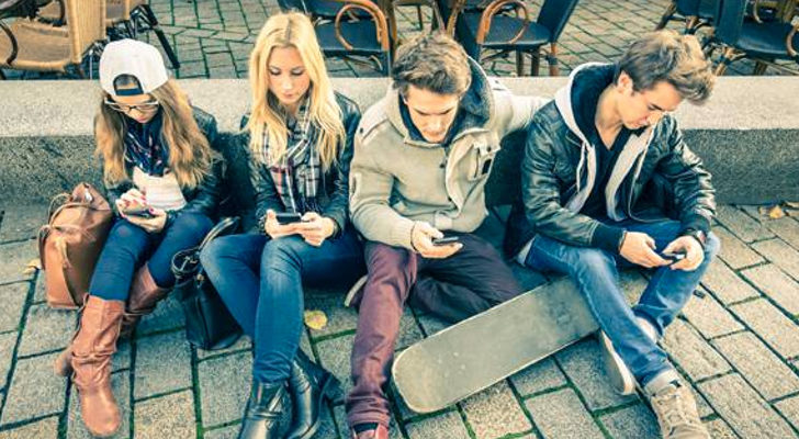 Varios jóvenes reunidos y mirando cada uno su móvil