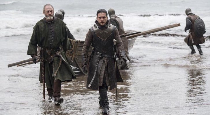 Ser Davos (Liam Cunningham) y Jon Nieve (Kit Harington) en RocaDragón en la séptima temporada e 'Juego de Tronos' con una barca y varios acompañantes más en la orilla