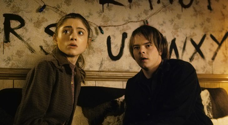 Natalia Dyer, Nancy Wheeler en la ficción , y Charlie Heaton como Jonathan Byers en una escena de 'Stranger Things' de Netflix con su característica pared de letras y luces de colores