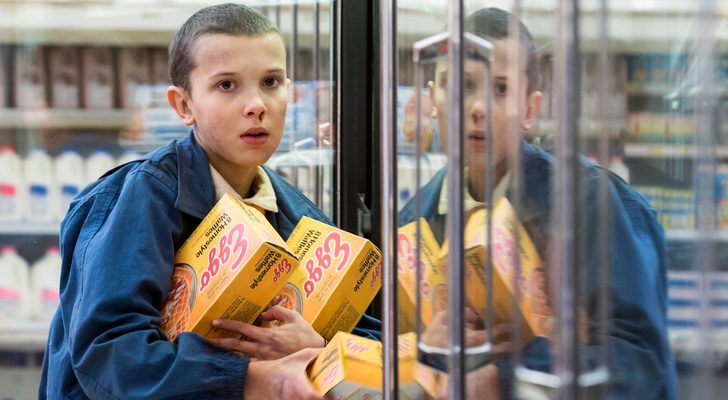 Once o Eleven, interpretada por Millie Bobbie Brown en un supermercado con varias cajas de gofres (waffles) en la primera temporada de 'Stranger Things', de Netflix